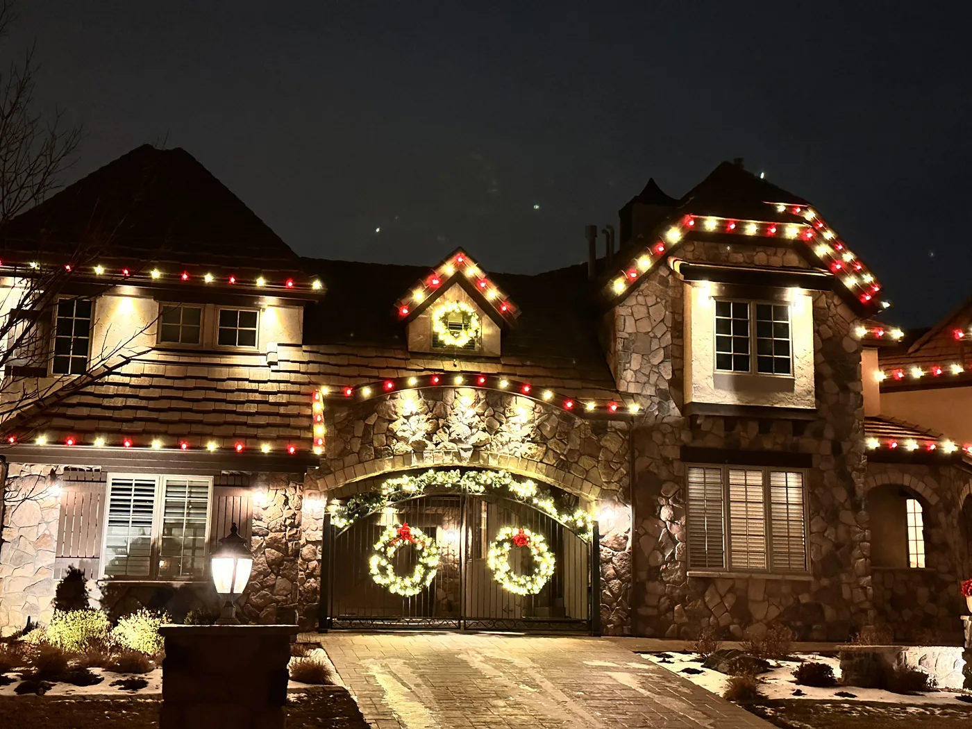 A Broomfield stone-fronted home in multicolour with lit wreaths over the entry and garage
