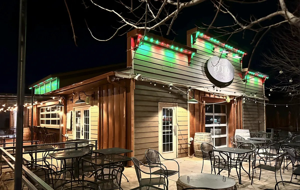 Echo Brewing in Erie, Colorado with its rooflines outlined in alternating red and green bulbs and warm string lighting over the patio at night