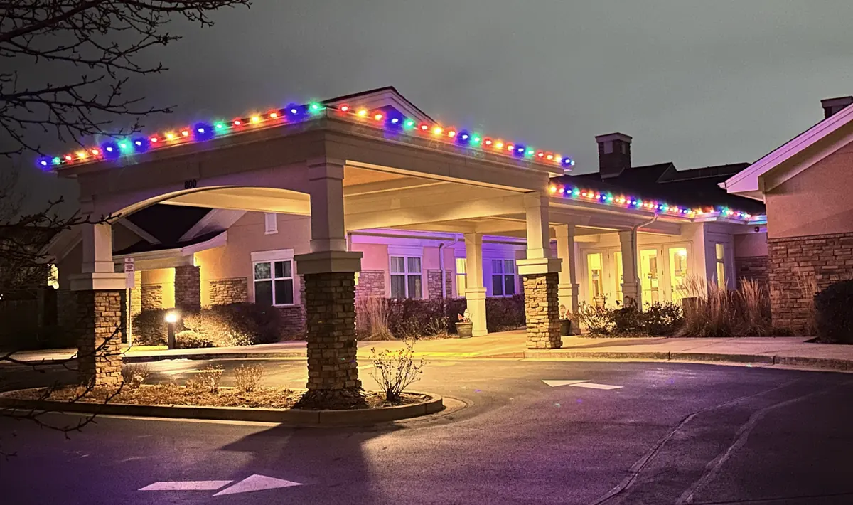 Commercial entrance portico outlined in multicolor bulbs at dusk, warm light under the canopy