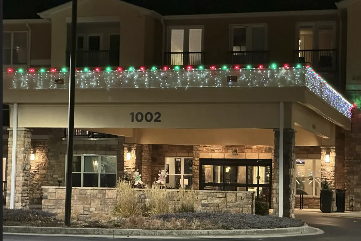 Senior living entrance canopy edged in red and green bulbs above a curtain of icicle lights