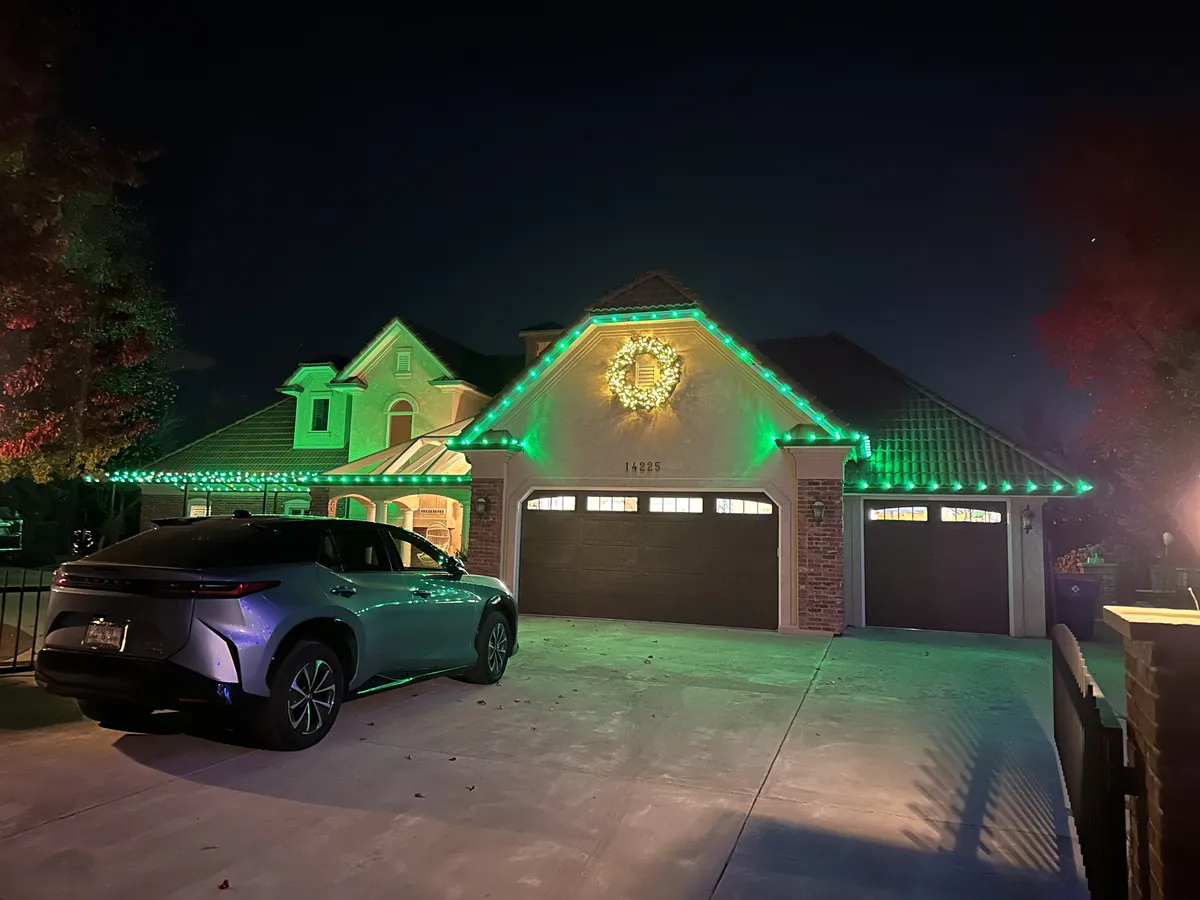 An Erie home washed in red and green with a lit wreath on the front gable