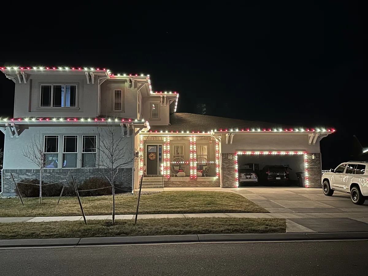 A Longmont two-story in red and white C9 bulbs with candy-cane wrapped porch columns