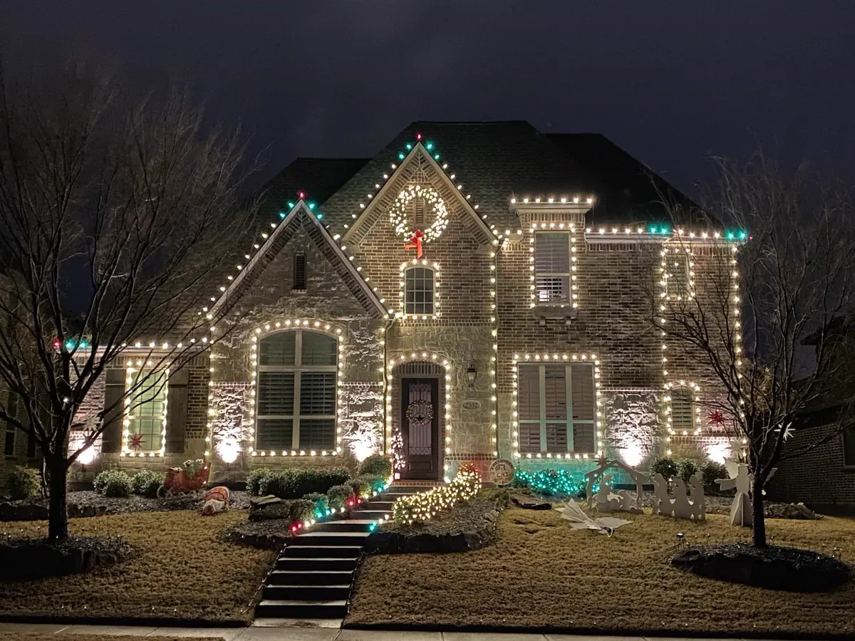 Two story home fully outlined in warm white holiday lighting