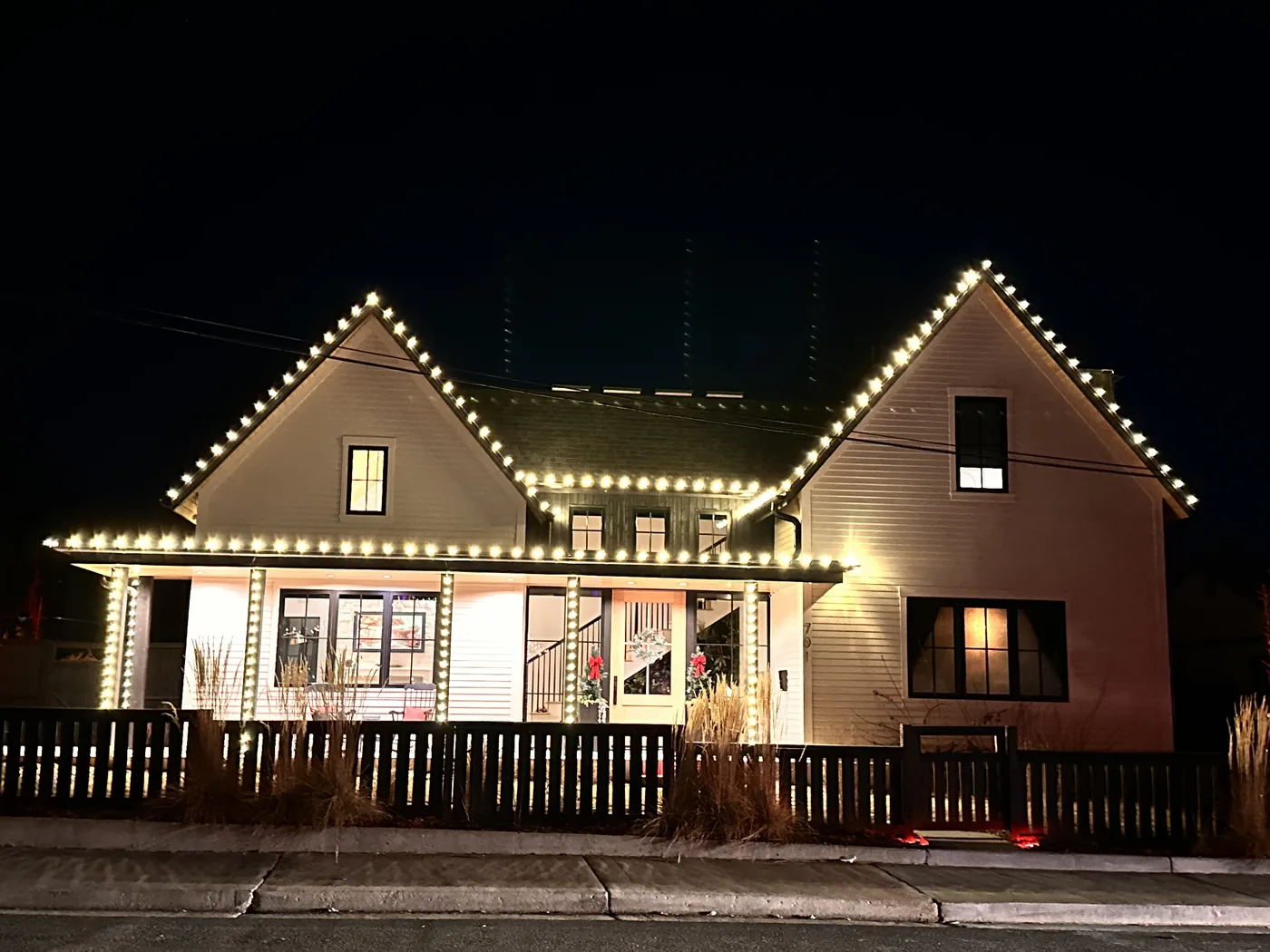 A Lafayette home with warm white bulbs along every roofline and gable, with the porch lit